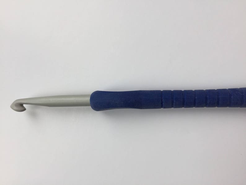 Puede incluir: Un gancho de ganchillo azul y plateado con un mango azul texturizado.