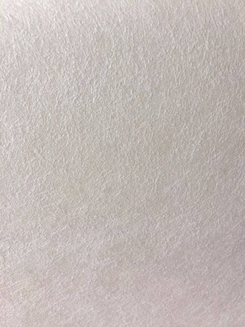 May include: A close-up of a white textured surface. The surface has a subtle, grainy texture.
