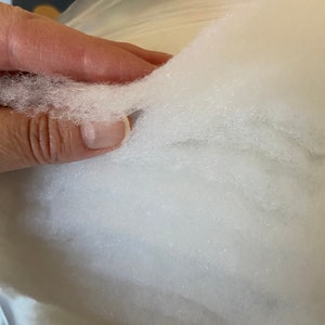 May include: Close-up of white, fluffy stuffing material. The stuffing is soft and appears to be made of synthetic fibers.