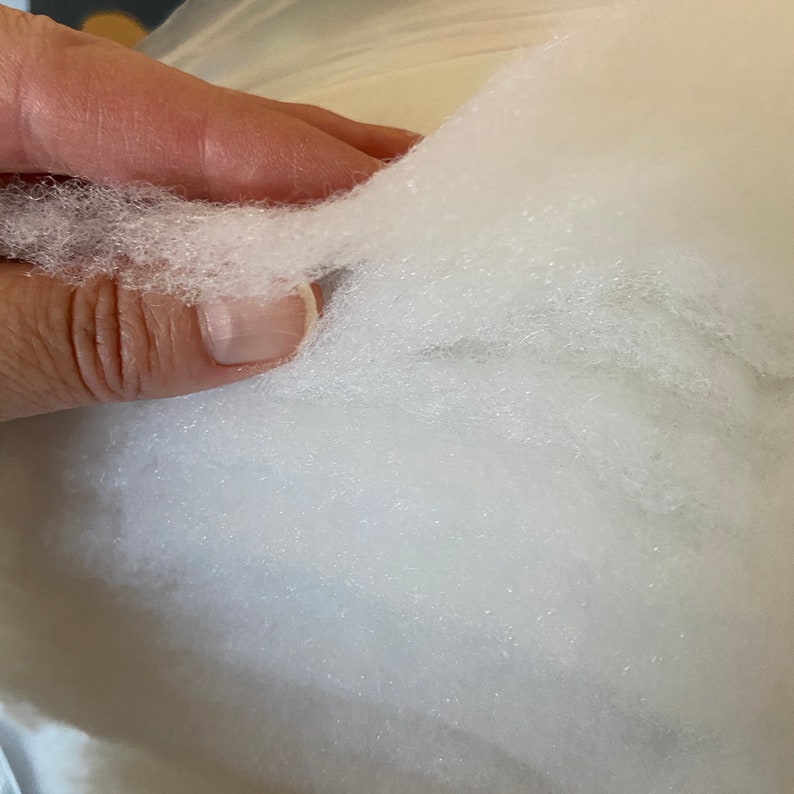 May include: Close-up of white, fluffy stuffing material. The stuffing is soft and appears to be made of synthetic fibers.