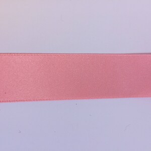 May include: A close-up of a pink satin ribbon.