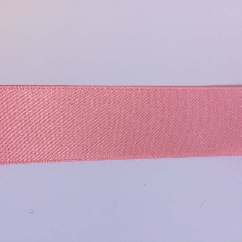 May include: A close-up of a pink satin ribbon.