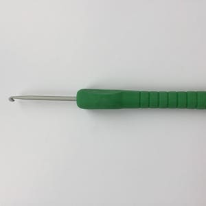 Puede incluir: Un gancho de ganchillo verde con un gancho de metal plateado.