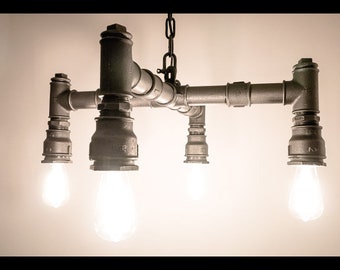 May include: A four-light industrial style chandelier made from black metal pipes and fittings. The chandelier has a simple design with four light bulbs hanging from the bottom.