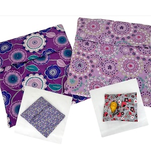 May include: Two purple fabric reusable food storage bags with floral patterns. One bag is folded and the other is open with a yellow lemon inside.