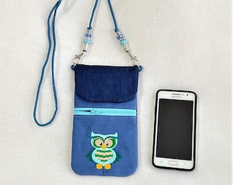 May include: A blue denim phone pouch with an embroidered owl design. The pouch has a zipper closure and a long blue strap with beads. A black smartphone is next to the pouch.