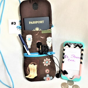 May include: A brown fabric phone case with a zipped pocket and a skull and cowboy boot design. The case is open and a passport is visible inside. A blue pen, a pair of headphones, and a key chain with keys are also visible. The case is hanging from a blue lanyard.