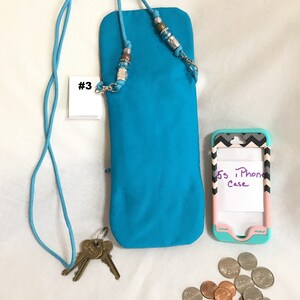 May include: A turquoise phone case with a beaded strap and a key chain. The case is labelled #3. A pink and grey phone case with the text "5s iPhone Case" is also pictured.