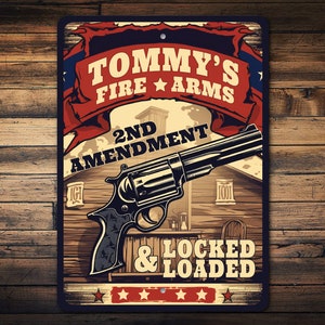 May include: A metal sign with a red, white, and blue color scheme. The sign features a cartoon image of a revolver with the text "Tommy's Fire Arms 2nd Amendment & Locked & Loaded".