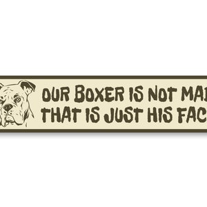 Puede incluir: Un letrero de metal beige con un contorno marr&oacute;n y una ilustraci&oacute;n en blanco y negro de un perro boxer. El letrero dice "Nuestro Boxer no est&aacute; enojado, esa es solo su cara."