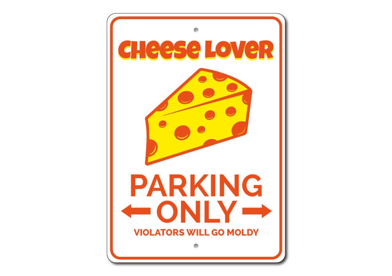May include: A white metal sign with orange text that reads "Cheese Lover Parking Only" with an arrow pointing to the left and an arrow pointing to the right. Below the text is a smaller orange text that reads "Violators Will Go Moldy". A cartoon image of a yellow wedge of cheese with orange spots is above the text.