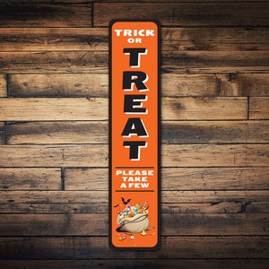 May include: Orange and black metal sign with the text "Trick or Treat" and "Please take a few". The sign features a cartoon illustration of a bag of sweets.