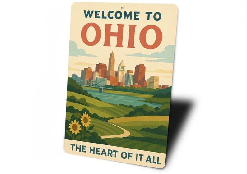 May include: A rectangular metal sign with a vintage design. The sign reads "WELCOME TO OHIO" in green and red letters above a skyline illustration. Below the skyline, the text reads "THE HEART OF IT ALL".