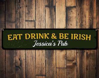 Puede incluir: Un letrero de metal verde y negro con el texto "Eat Drink & Be Irish" en letras amarillas y "Jessica's Pub" en letras blancas.