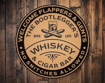 May include: A round, brown and black sign with the text "Welcome Flappers & Gents The Bootlegger's Late Whiskey & Cigar Bar No Snitchers Allowed".