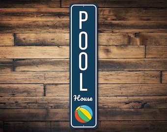 Puede incluir: Un letrero de metal azul y blanco con la palabra "POOL" en letras blancas y las palabras "House" y una pelota de playa colorida debajo.