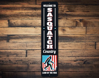 Letrero metálico de bienvenida al País de Sasquatch – Decoración patriótica de pared con temática de Pie Grande, letrero para cabaña con la bandera de EE. UU., arte divertido para exteriores, regalo para fanáticos de Pie Grande