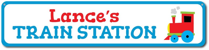 May include: A blue and white sign with the text "Lance's Train Station" in red and blue letters. A red toy train with yellow and green accents is on the right side of the sign.