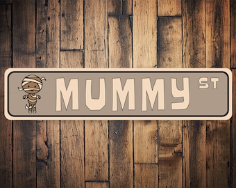 May include: A brown and white sign with the text "MUMMY ST" in white letters. A cartoon mummy is on the left side of the sign.