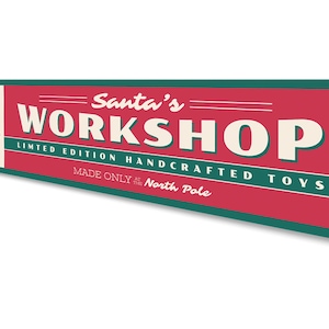 May include: A red and green metal sign with the text "Santa's Workshop" in white. The sign also includes the text "Limited Edition Handcrafted Toys Made Only at the North Pole". A cartoon image of Santa Claus is in the upper left corner of the sign.