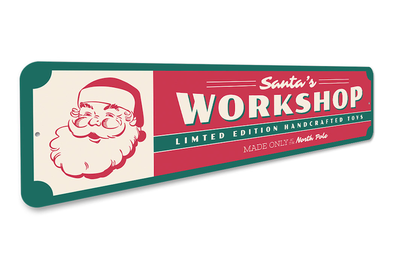 May include: A red and green metal sign with the text "Santa's Workshop" in white lettering. The sign also includes the text "Limited Edition Handcrafted Toys" and "Made Only for the North Pole". A cartoon image of Santa Claus is on the left side of the sign.