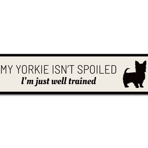 May include: A white metal sign with black text and a black silhouette of a Yorkshire Terrier. The text reads "My Yorkie isn't spoiled I'm just well trained."