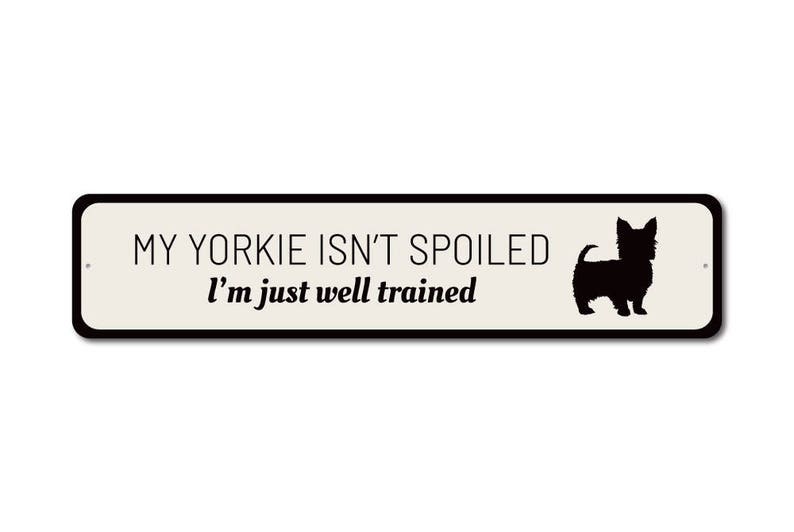 May include: A white metal sign with black text and a black silhouette of a Yorkshire Terrier. The text reads "My Yorkie isn't spoiled I'm just well trained."