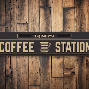 May include: A black and gold sign with the text "Lainey's Coffee Station" and a stylized image of a coffee cup.