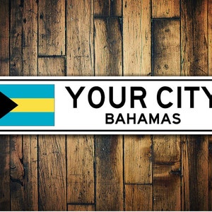 May include: White metal sign with the text "YOUR CITY BAHAMAS" and a depiction of the Bahamian flag.