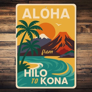 May include: A rectangular sign with a vintage travel poster design. The sign features a Hawaiian landscape with palm trees, a volcano, and the text "ALOHA from HILO TO KONA" in a retro font, set against a yellow and orange background.