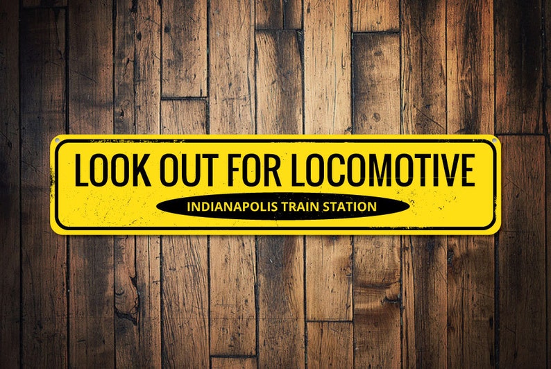 May include: Yellow warning sign with black text that reads "LOOK OUT FOR LOCOMOTIVE" and "INDIANAPOLIS TRAIN STATION". The sign has a distressed, vintage look.