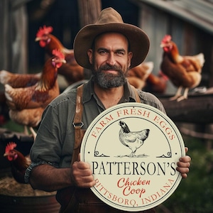 May include: A man in a brown hat and overalls holds a round sign that says "Farm Fresh Eggs Patterson's Chicken Coop Pittsboro, Indiana". The sign has a white background with black text and a black and white illustration of a chicken.