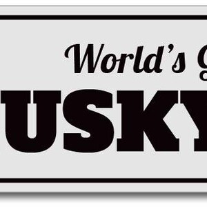 May include: A white metal sign with black text and a black silhouette of a husky dog. The sign reads "World's Greatest Husky Dad".