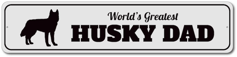 May include: A white metal sign with black text and a black silhouette of a husky dog. The sign reads "World's Greatest Husky Dad".