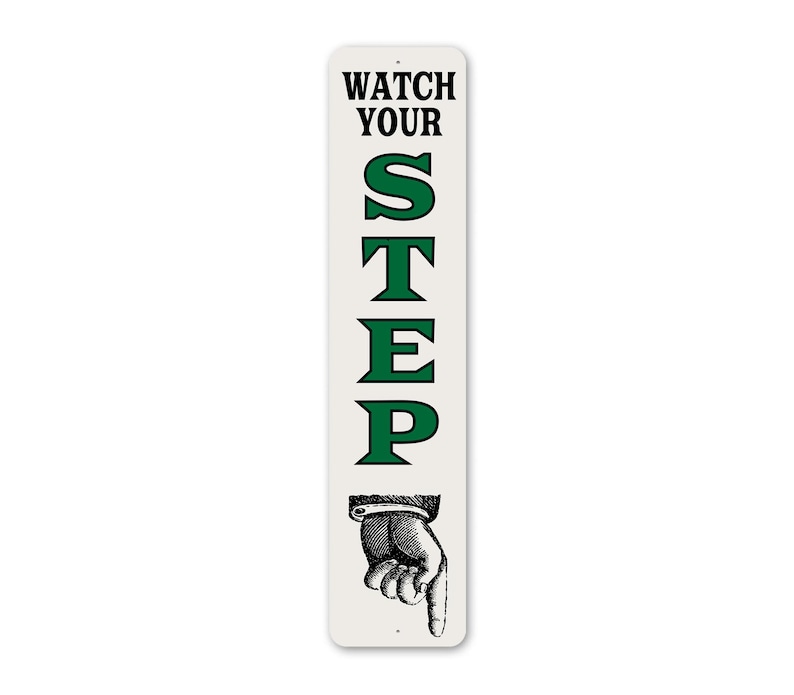 A sign with the text "WATCH YOUR STEP" in green letters, accompanied by a hand pointing downwards.