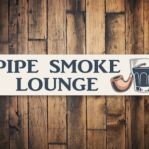 以下が含まれることがあります： 「PIPE SMOKE LOUNGE」と黒文字で書かれた白い長方形の看板。看板の右側には、茶色のパイプと暗い液体の入ったグラスが描かれている。