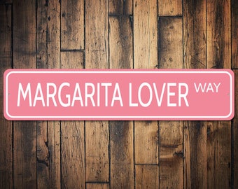 May include: Pink metal sign with white text that reads "Margarita Lover Way".