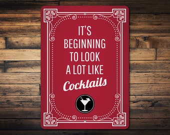 Op de afbeelding: Rood metalen bord met een witte, sierlijke rand en de tekst "It's beginning to look a lot like cocktails" met een cocktailglas-icoon.