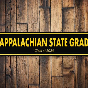 以下が含まれることがあります： 「Appalachian State Grad」と「Class of 2024」の文字が書かれた黒と黄色の看板。