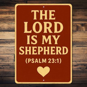 May include: A rectangular sign with the text "THE LORD IS MY SHEPHERD (PSALM 23:1)" in a serif font. The sign is a dark red color with a gold border and text. A gold heart is at the bottom.