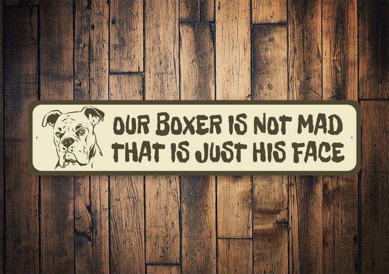 Puede incluir: Un letrero de metal marr&oacute;n con fondo blanco. El letrero presenta una imagen de dibujos animados de un perro boxer con el texto "Our Boxer is not mad that is just his face."