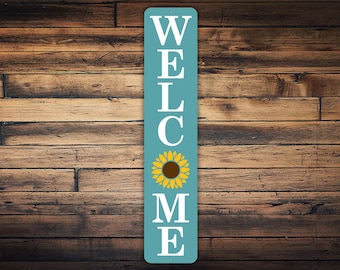 May include: A blue vertical welcome sign with white letters spelling "WELCOME" and a yellow sunflower in the center.