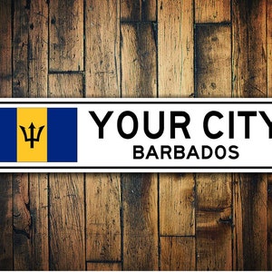 May include: White metal sign with a blue and yellow flag of Barbados and the text "YOUR CITY BARBADOS".