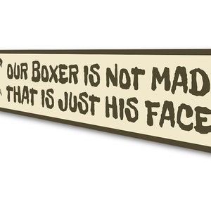 Puede incluir: Un letrero de metal marr&oacute;n con fondo beige. El letrero presenta una imagen de dibujos animados de un perro boxer con el texto "Our Boxer is not mad that is just his face."