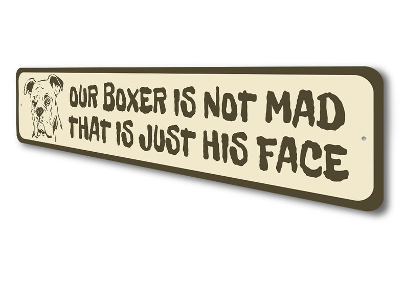 Puede incluir: Un letrero de metal marr&oacute;n con fondo beige. El letrero presenta una imagen de dibujos animados de un perro boxer con el texto "Our Boxer is not mad that is just his face."