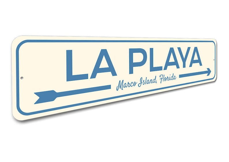 May include: A blue and white metal sign with the text "LA PLAYA" and "Marco Island, Florida". An arrow points to the right.