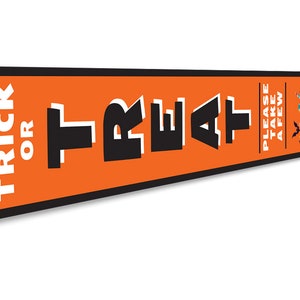 May include: Orange and black metal sign with the text "Trick or Treat" and "Please take a few". The sign has a cartoon image of a witch's cauldron overflowing with sweets.