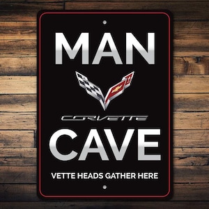 K&ouml;nnte beinhalten: Schwarzes und rotes Metallschild mit dem Text "Man Cave" und einem Corvette-Logo. Der Text "Vette Heads Gather Here" befindet sich am unteren Rand des Schildes.