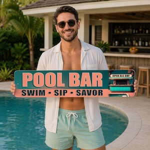 May include: A rectangular pool bar sign with the words "POOL BAR" in large, coral-colored letters. Below, the words "SWIM • SIP • SAVOR" are displayed. The sign also features a small illustration of a bar and the text "OPEN ALL DAY".