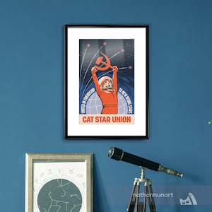 May include: Framed poster with a retro design, depicting a cat in a spacesuit holding a hammer and sickle. The poster's text reads "CAT STAR UNION", with additional text: "UNITED IN FRIENDSHIP" and "TO NEW RISING STARS". The colour scheme is predominantly blue and orange.